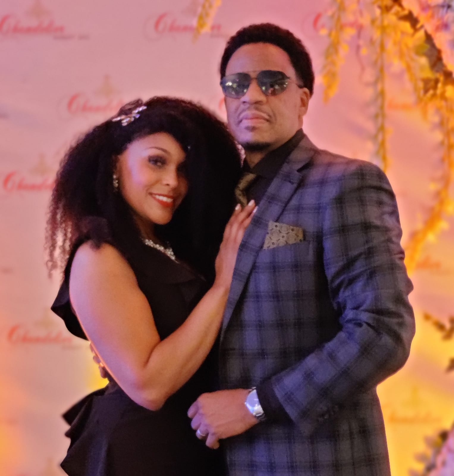 A couple in evening dress at a step-and-repeat backdrop.