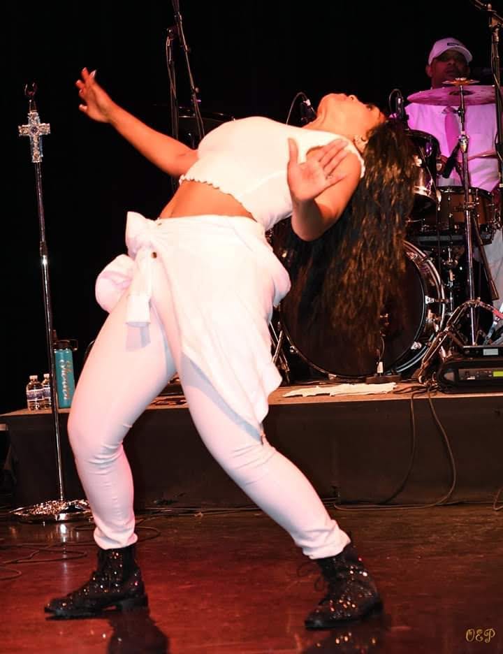 Leaning back mid-song under stage lights, one arm raised.